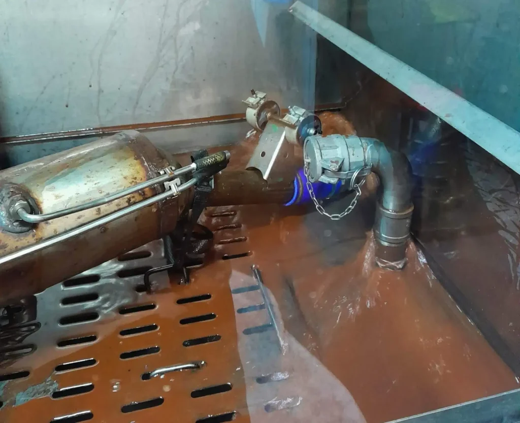 Ausgebauter Partikelfilter mit Schlauchanschlüssen in der Reinigungskammer